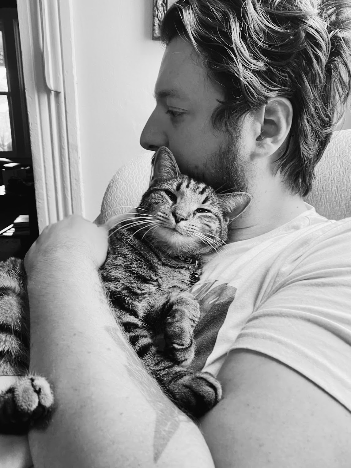 Tanner holding a sleepy tabby cat, in black and white