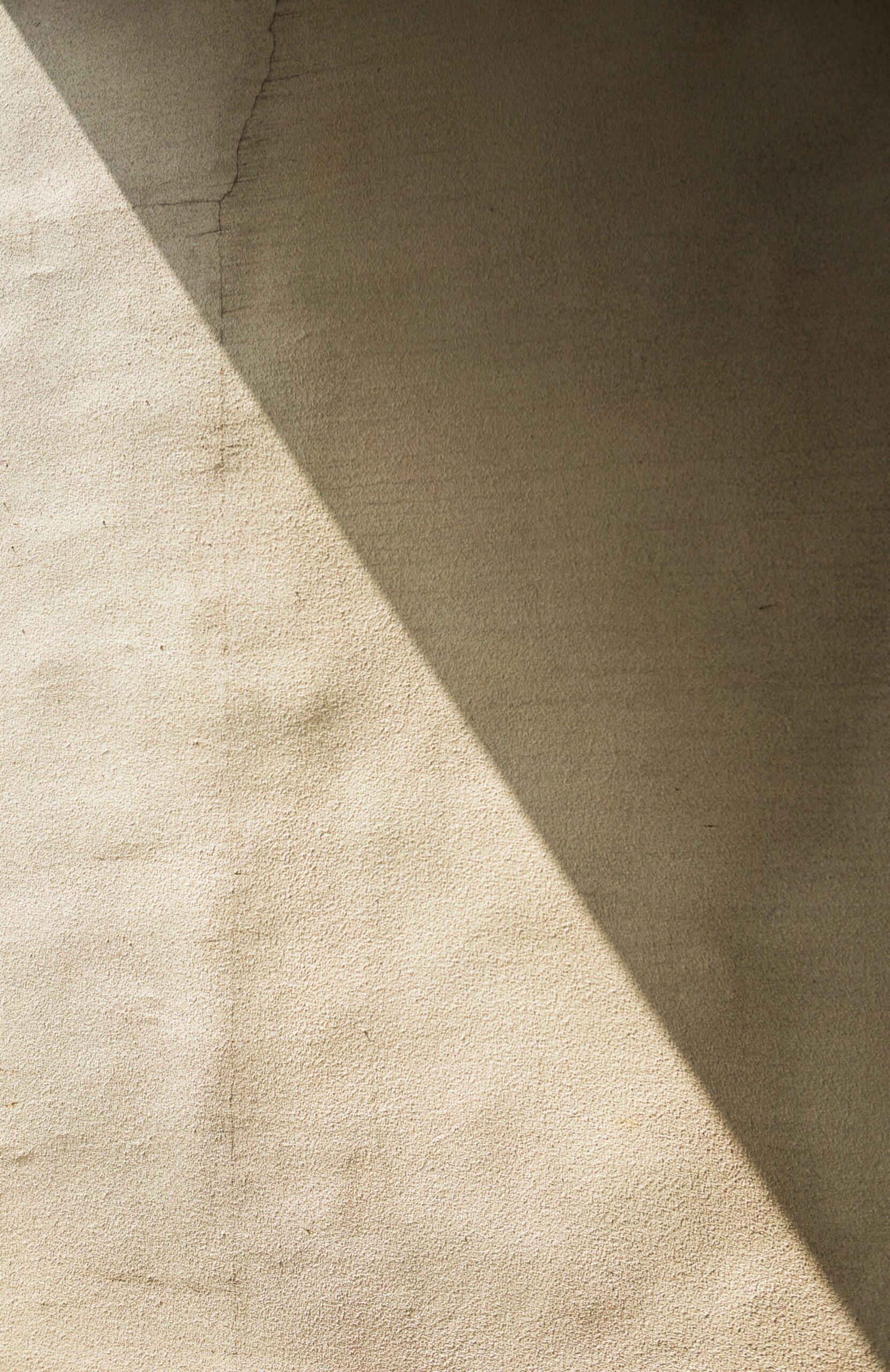 Warm plaster wall crossed by a diagonal band of shadow