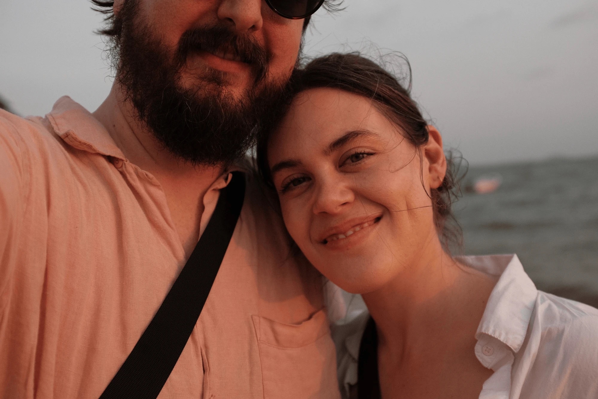 Tanner and Katie cheek to cheek by the sea at dusk
