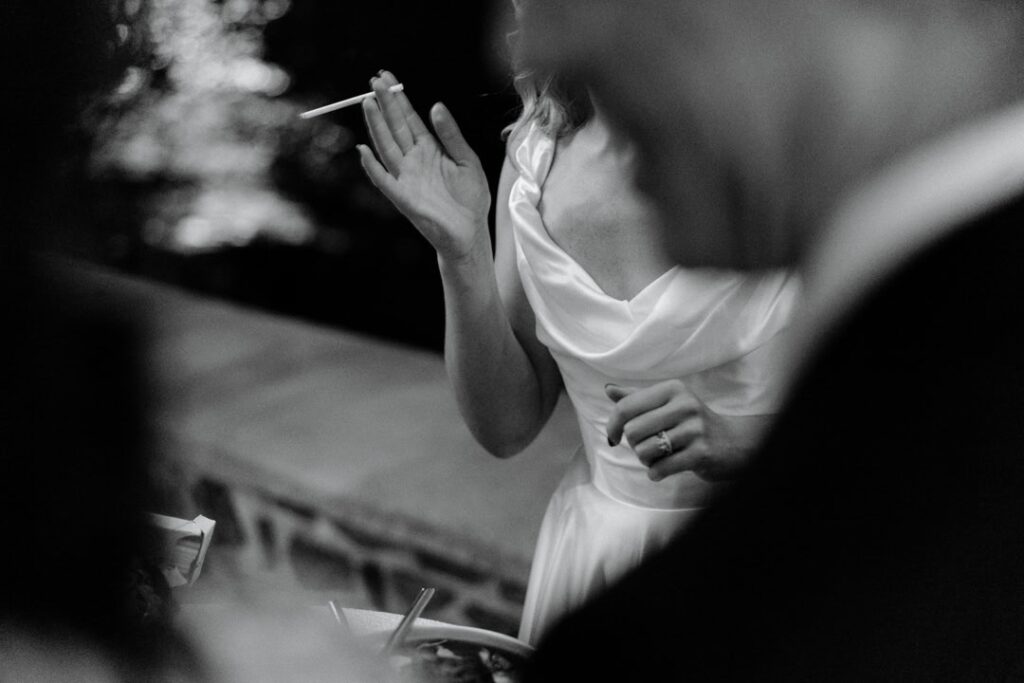 A bride at a candlelit reception, laughing, in black and white
