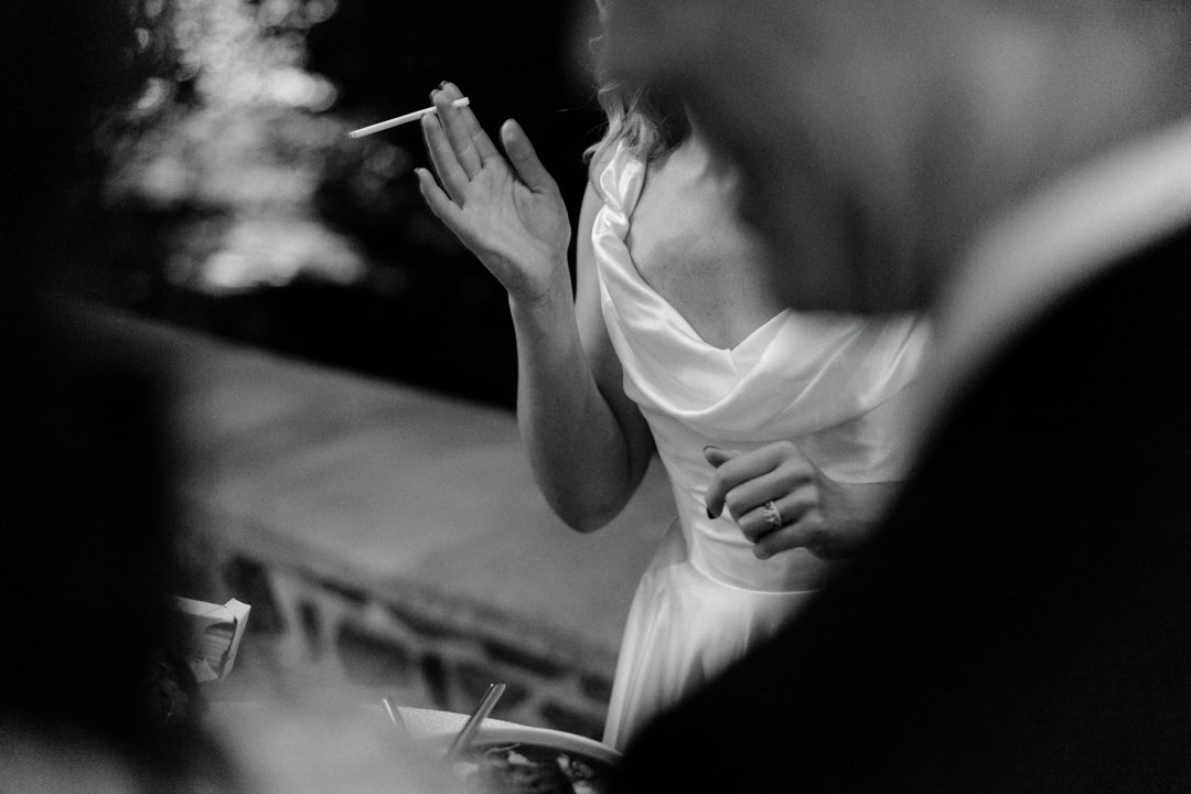 A bride at a candlelit reception, laughing, in black and white